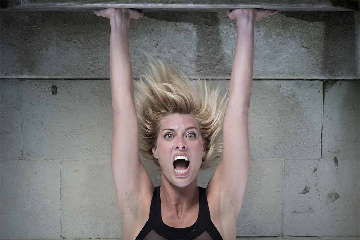 Photograph of a woman model in a strained handstand, shown upside-down